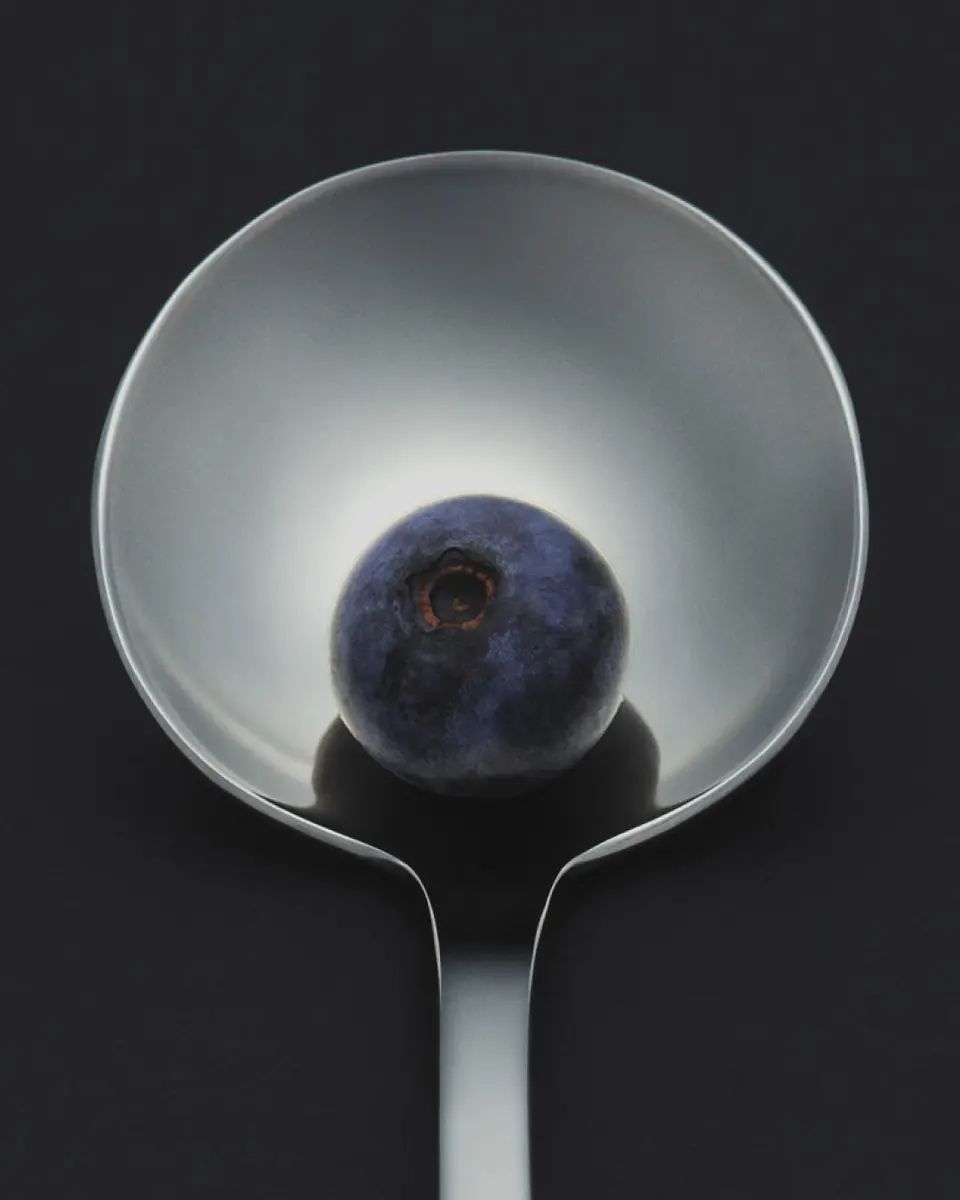 metal spoon housing a blueberry on its rounded edge